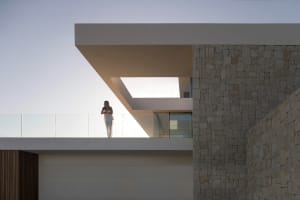 Woman standing on a balcony overlooking a city view with a stone building in the background