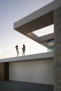 Two women standing on a balcony overlooking an urban landscape with buildings in the background