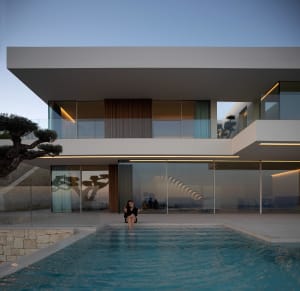 A modern pool scene with clear water, surrounded by a large white building and people relaxing in the area