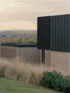 A traditional house with a brick exterior, a black doorway, and a sturdy appearance, set against a daytime backdrop