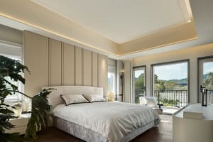 A calm and inviting bedroom with a white bed, two chairs, and a potted plant, creating a serene atmosphere