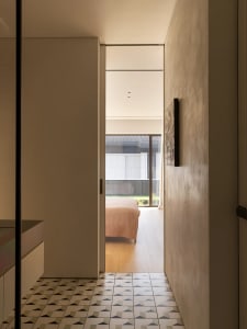 Cozy bedroom with a bed near the center, two chairs, and a couch, with natural light entering through a nearby window
