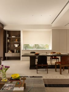 Modern kitchen and dining area with a large window, two chairs, a table, sink, refrigerator, and various decorative items
