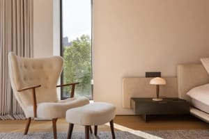 A well-lit living area with a white chair in front of a window, accompanied by a smaller chair in the background, creating a comfortable and inviting atmosphere