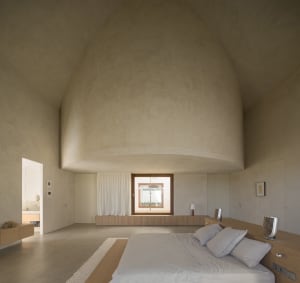 Modern bedroom with a large bed on a wooden platform, two windows, and a minimalist design