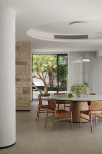 Empty dining area with a large wooden table and four chairs, surrounded by a clean and minimalist space