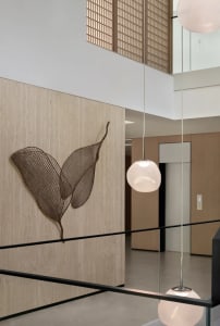 A modern living-dining space with a wire leaf artwork, comfortable seating, and stylish decor