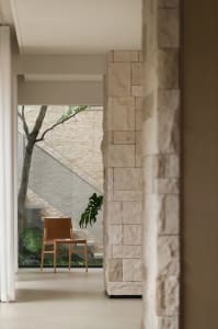 A calm and inviting room with a wooden chair in front of a window, surrounded by potted plants and natural light