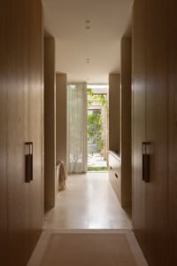 A bright and inviting hallway with a white tile floor, large window, and two doors leading to a living area
