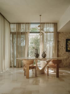 Cozy dining space with a wooden table and chairs, surrounded by curtains that allow natural light and maintain privacy