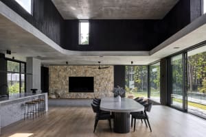 Sleek modern living room with a stone fireplace, black chairs, and a TV mounted above, surrounded by contemporary design elements