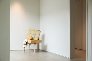 Empty room with a wooden table and chair, featuring a white wall and two boxes placed side by side on the table