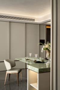 Elegant dining room with gray walls, a dining table, chairs, wine glasses, and a vase with flowers