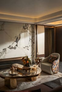 Elegant living space with a glass table, chairs, and a couch, surrounded by a sophisticated atmosphere with a vase of flowers