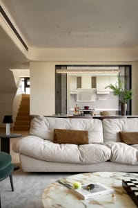 Inviting living area with a white couch, kitchen island, potted plants, and a vase, creating a cozy atmosphere