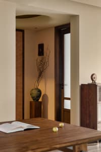 Cozy room with a wooden table, vase, and two doors, featuring traditional design with warm and functional elements