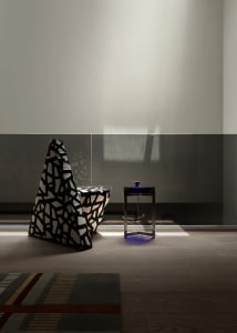 Dimly lit living room with a black and white chair, two tables, and a cozy atmosphere