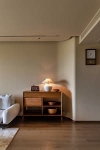 Cozy living room with wooden floors and white walls, featuring two couches, a clock, and a small table with a bowl