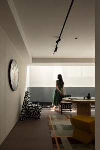 Modern dining space with a black and white theme, featuring a dining table and chairs, a clock on the wall, and a woman standing near the table