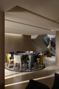 A modern dining space with a colorful array of chairs surrounding a dining table, set for a game night with cups and bowls, and a nearby couch adding to the cozy atmosphere