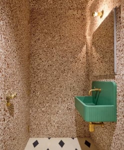 Bathroom with a metal sink, two sinks, and a shower head, set against a tiled wall
