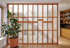 A well-lit home office with wooden blinds, two potted plants, and a calm atmosphere