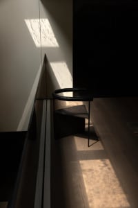A living area with two chairs, one near the left and one near the right, on a warm hardwood floor