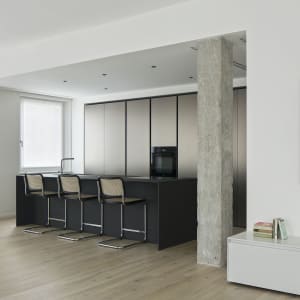 Modern kitchen with black cabinets, wooden floors, and a dining area with four chairs and a table