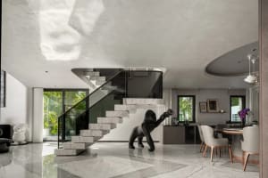 A modern living space with a black monkey statue, two chairs, and decorative vases in a white room