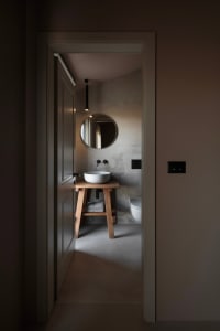 Bathroom with a wooden sink stand, mirror, and toilet, featuring a simple and functional design