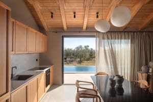 Open living area with wooden floors and cabinets, featuring a dining table, chairs, and decorative bowls in a warm and inviting atmosphere