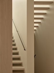 A narrow stairwell with wooden steps and a white color scheme, set against a blank background