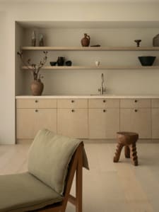 Modern kitchen with white walls, wooden floors, and decorative vases, featuring a sink and wooden cabinets