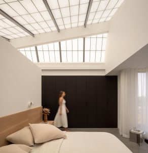 A calm and inviting bedroom with a large bed, white sheets, and a couch on the left side, two people are present in the room