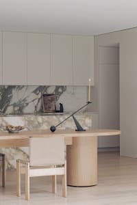 Warm and inviting modern kitchen with marble countertops, a wooden dining table, and white cabinets