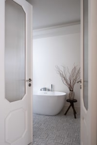 A clean and organized bathroom with a white bathtub, two vases, and a potted plant, emphasizing functionality and simplicity