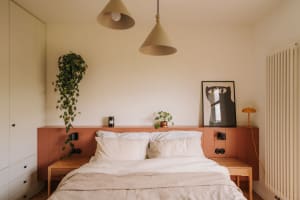 Cozy bedroom with a wooden platform bed, white bedding, and potted plants, with a warm and inviting atmosphere