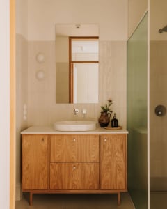 Modern bathroom with a sink and mirror above, two bottles on the countertop, and a shower area