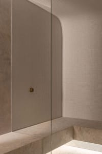 Bathroom with a white tile shower wall, glass door, and a bench, creating a calm and relaxing atmosphere
