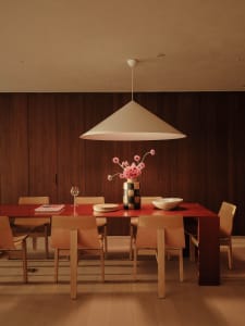 Warm and inviting dining space with a large wooden table, wine glasses, and bowls, surrounded by multiple chairs