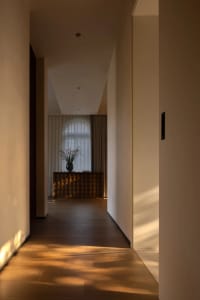 Empty hallway with a wooden floor and white walls, featuring two vases placed on the floor