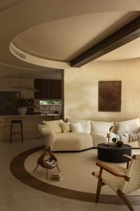 Open living area with white walls, beige furniture, and decorative elements, featuring a kitchen, dining area, and living room