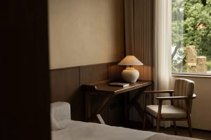 Cozy bedroom with a bed, chair, desk, and lamp, creating a warm and inviting atmosphere