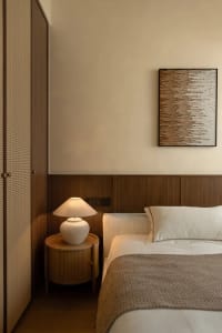 A bedroom with a wooden theme, featuring a large bed with white sheets and pillows, two lamps, and neutral-toned walls, creating a calming and inviting space for relaxation