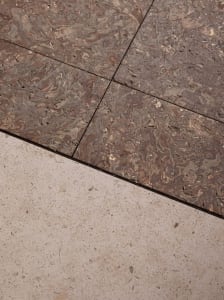 A modern living space with a tiled floor, featuring a combination of wood and stone materials, natural light, and a clean design
