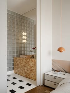 A modern bathroom with a white tile floor, white sink, and large mirror, featuring natural light and a bright, inviting atmosphere