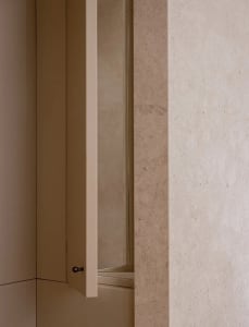 A dimly lit bathroom with a wooden door and a glass window, visible through the open door