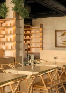 A modern restaurant with a wooden floor, filled with furniture, creating a cozy and inviting atmosphere with soft lighting