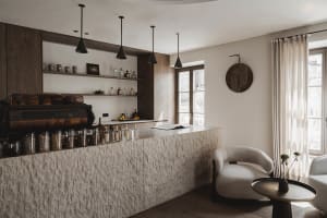 A kitchen with a marble counter, a chair, and a clock on the wall, creating a cozy and inviting atmosphere