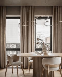 A well-lit living room with a dining table, chairs, and a vase, featuring a mix of wood and glass materials in a modern and inviting space